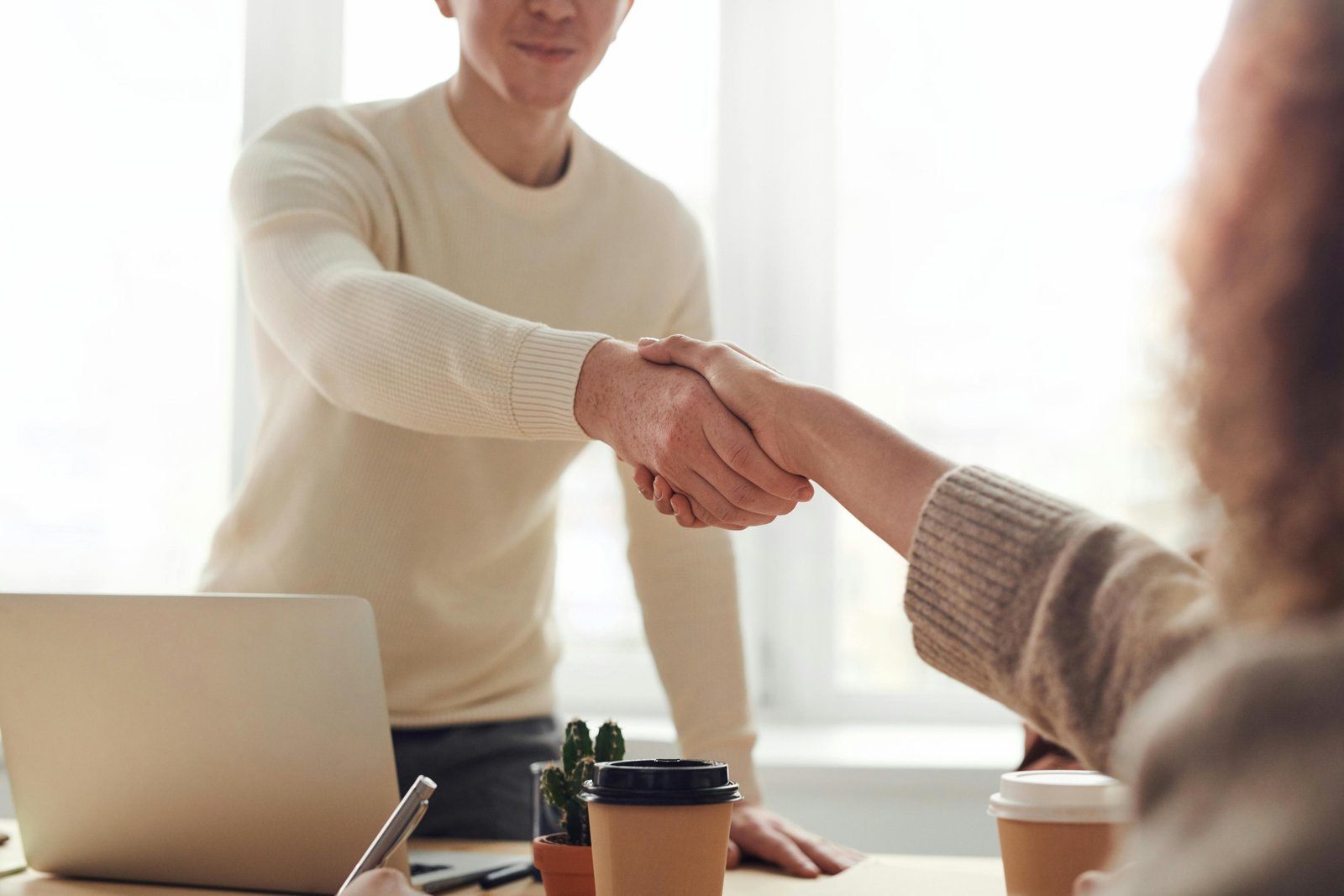 Home Close-up of professionals shaking hands over coffee in a modern office.
