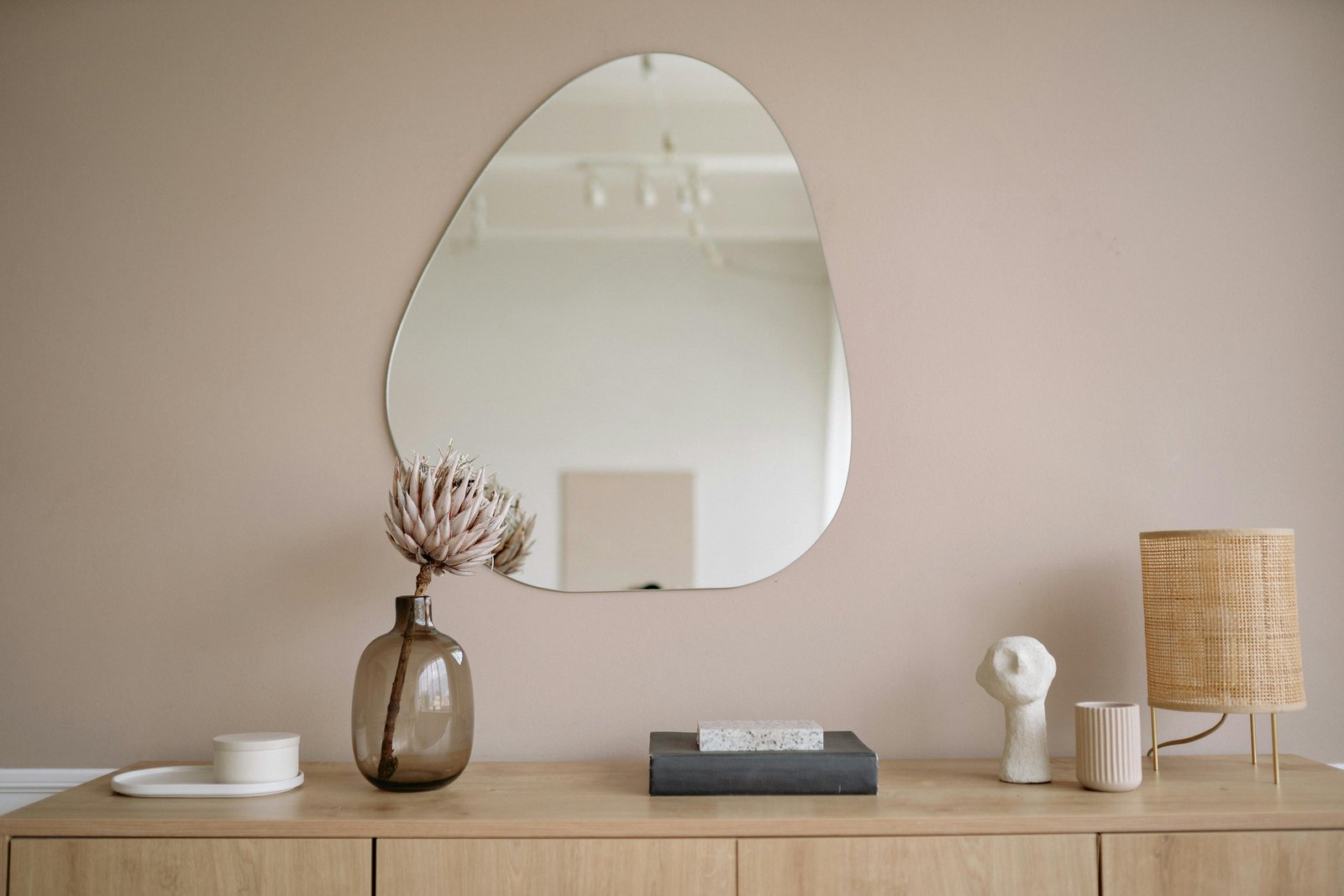 Home Stylish minimalist interior featuring a mirror, decorative vase, and lamp.